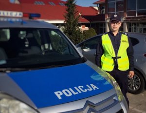 Policjant dzielnicowy stoi przy radiowozie.