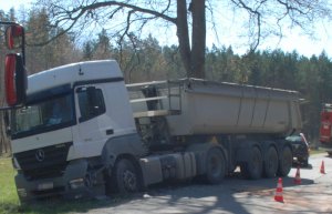 Miejsce zdarzenia drogowego na drodze wojewódzkiej W 218 oraz widoczny przód i prawy bok samochodu ciężarowego uczestniczącego w zdarzeniu drogowym.