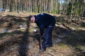 Pierwszy Zastępca Komendanta Powiatowego Policji w Wejherowie przygotowuje dołki do wsadzenia sadzonek drzew.