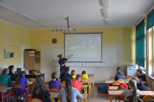 Policjantka podczas spotkania w klasie, prezentuje film profilaktyczny z zakresu bezpieczeństwa pieszych.