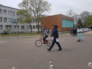 Policjantka nadzoruje przebieg konkurencji praktycznych - jazda rowerem po torze przeszkód.