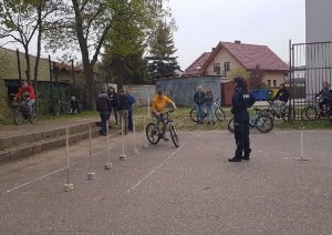 Policjantka nadzoruje przebieg konkurencji praktycznych - jazda rowerem po torze przeszkód.