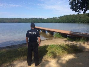 Policjant kontroluje plażę nad jeziorem Zawiat w Bieszkowicach