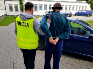 Mężczyzna jest prowadzony przez policjanta.