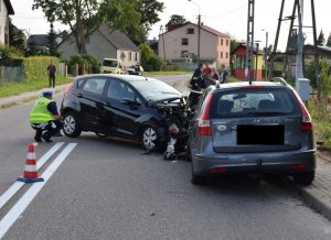 Policjant ruchu drogowego wykonuje oględziny samochodu osobowego.