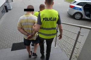 Policjanci prowadzą zatrzymanego do radiowozu