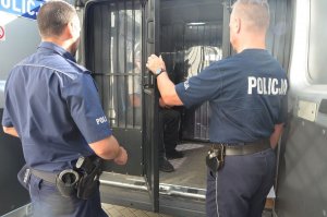 Policjanci doprowadzają poszkiwanego męzczyznę do AŚ w Wejherowie