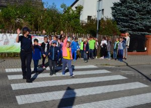 Policjantka na przejściu dla pieszych uczy dzieci zasad bezpieczeństwa.