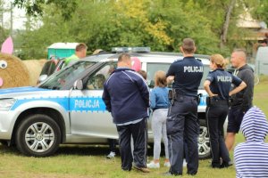 Policjanci na festynie prezentują uczestnikom policyjny radiowóz.