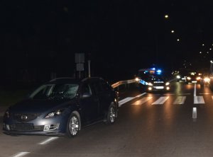 Policjanci wykonują czynności na miejscu zdarzenia. Na pierwszym planie widoczny jest samochód mazda z popękaną przednią szybą.