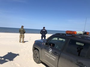 Patrol policjant i strażnik leśny kontrolują plażę