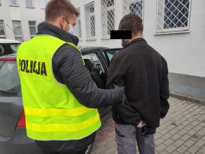 Policjant konwojuje zatrzymanego do porkuratury