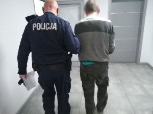 Policjant prowadzi zatrzymanego mężczyznę