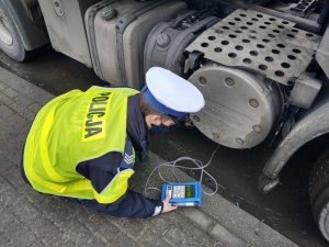 Policjant urządzeniem pomiarowym bada jakość spalin w samochodzie ciężarowym