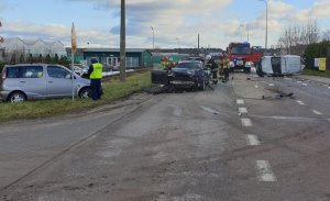 policjant pracuje na miejscu wypadku, w tle widać trzy uczestniczące samochody