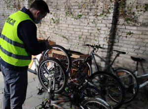 Policjant stoi przy rowerach, wykonuje ich oględziny.