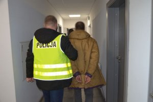 Policjant prowadzi zatrzymanego mężczyznę