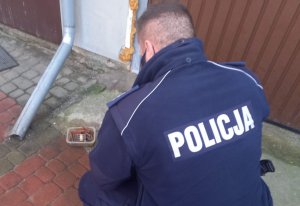 Policjant ogląda leżące na ziemi plastikowe pudełko w którym leżą długie naboje.