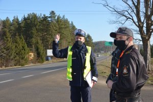 Policjant oraz członkowie komisji rozmawiają na miejscu wypadku i sprawdzają infrastrukturę drogową.