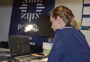 Policjantka siedzi przy biurku, przed nią widać uruchomiony komputer laptop a na nim widoczne są okienka w programie teams do nauki zdalnej.