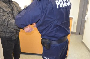 Policjant zakłada kajdanki zatrzymanemu