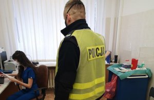 Policjant w odblaskowej kamizelce oczekuje w gabinecie pielęgniarki na szczepienie