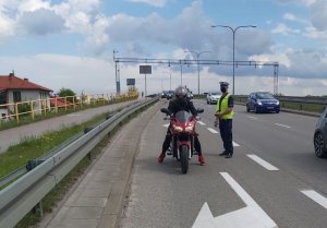 Policjant zatrzymuje do kontroli drogowej motocyklistę.