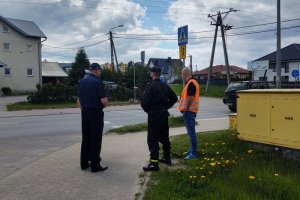 Policjant stoi ze strażakiem i zarządcą drogi przy przejściu dla pieszych.