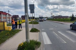 Policjant stoi ze strażakiem i zarządcą drogi przy przejściu dla pieszych.