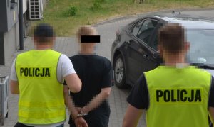 Policjanci prowadzą zatrzymanego do samochodu.