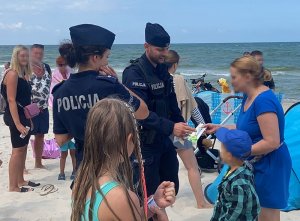 Policjanci rozmawiają z turystami, , rozdają opaski niezgubki i elementy odblaskowe.