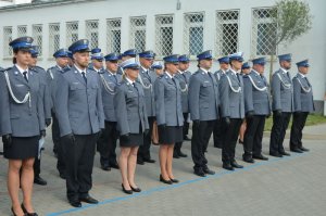 Policjanci stoją w rzędzie na baczność.