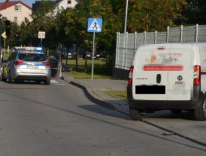 Po prawej stronie stoi na poboczu dostawczy fiat, a za nim w tle na jezdni policyjny radiowóz, który blokuje pas ruchu