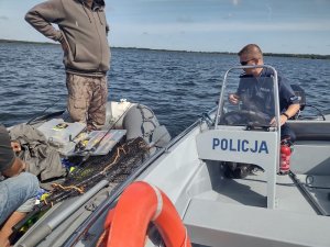 Policjant na motorówce kontroluje rybaków na łodzi