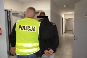 Policjant prowadzi zatrzymanego mężczyznę