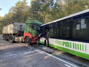 Widoczny jest rozbity przód samochodu ciężarowego i autobusu