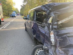 Widoczny tył rozbitego ciemno-grafitowego mercedesa vito, po przeciwnej stronie jezdni widoczny jest autobus a za nim w oddali policyjny radiowóz.