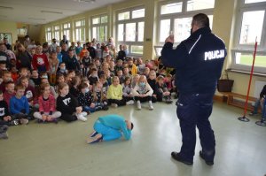 Policjant stoi na holu i prowadzi spotkanie z dziećmi