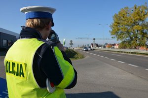 Policjant wykonuje pomiar na drodze krajowej.