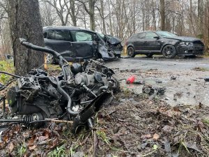 Na pierwszym planie silnik, który wypadł z samochodu, a w oddali dwa rozbite samochody.