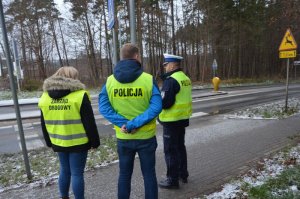 Policjant ruchu drogowego, zarządca drogi oraz policjant dochodzeniowo śledczy rozmawiają na miejscu zdarzenia.