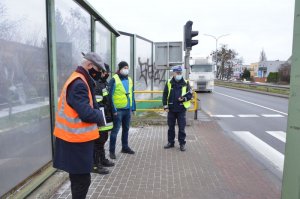 Komisja w składzie Policjanta w umundurowaniu ruchu drogowego, policjanta w ubiorze cywilnym w kamizelce odblaskowej oraz strażaka i zarządca drogi rozmawiają na chodniku, przy ekranach energochłonnych przy wejściu na przejście dla pieszych.