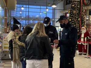 Policjanci rozmawiają z trzema kobietami, dwie z nich są odwrócone tyłem, jedna jest bokiem.