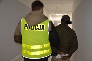 Policjant prowadzi zatrzymanego mężczyznę.