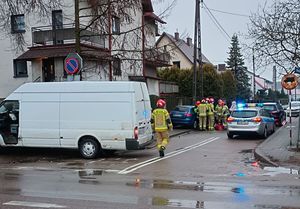 Po lewej stronie widoczny jest transit, po prawej przy chodniku stoi radiowóz, potem na tej jezdni widoczny jest po lewej stronie do radiowozu niebieski audi a przy nim stoją strażacy