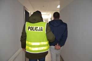 Policjant wprowadza zatrzymanego na schody.