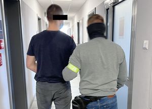 Policjant prowadzi zatrzymanego mężczyznę