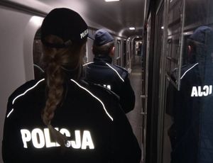 Policjantka z policjantem idą korytarzem w pociągu dalekobieżnym.