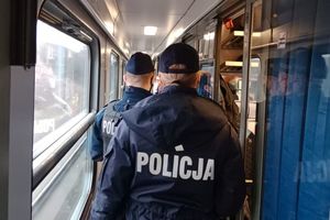 Policjanci idą korytarzem w pociągu dalekobieżnym.