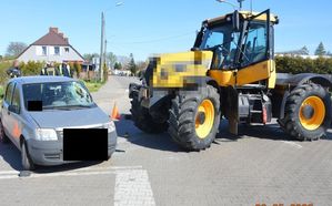 Na zdjęciu widoczne są dwa samochody, po lewej samochód osobowy fiat z rozbitą szybą po prawej stronie oraz obok ciągnik siodłowy. W tle za samochodem stoi policjant oraz strażacy.